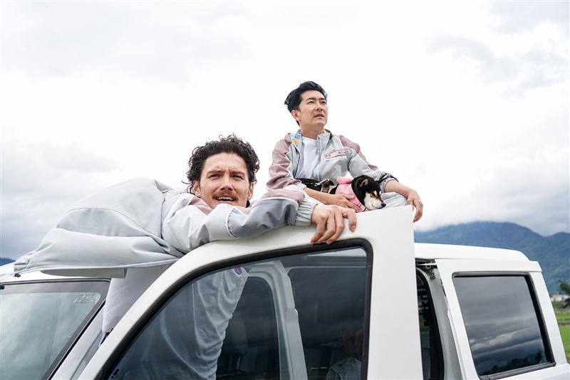 施名帥（右）擔任片頭導演，在車頂吹冷風吹到頭痛、髮型失守。（圖／客台提供）