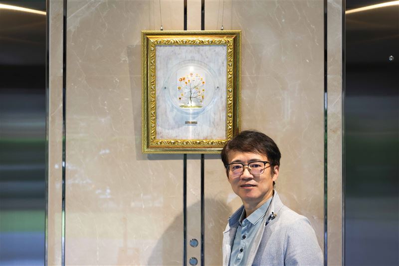 黃憶人 ╳ 慕舍《AMBER BOY 的異想世界》—臺灣琥珀藝術家黃憶人與作品「演化之樹」合影。(圖/飯店旅宿業者提供)
