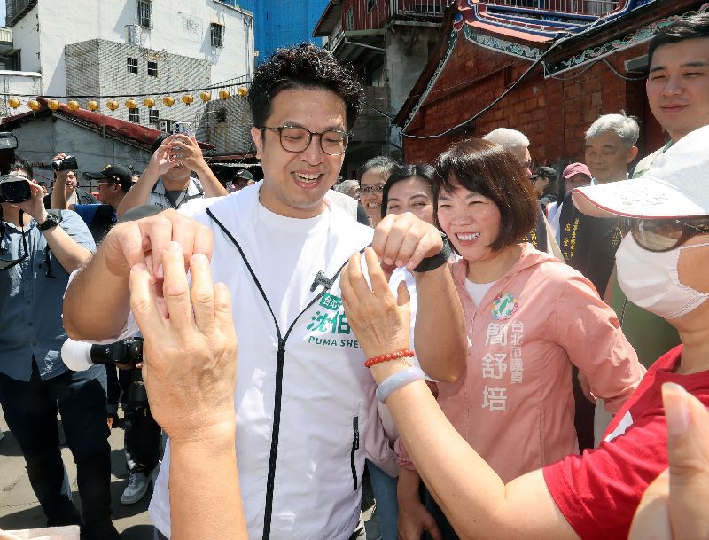 民進黨台北市長參選人沈伯洋（前左）20日上午赴景美集應廟參拜後，前往景美市場掃街，與市民朋友合比愛心互動。中