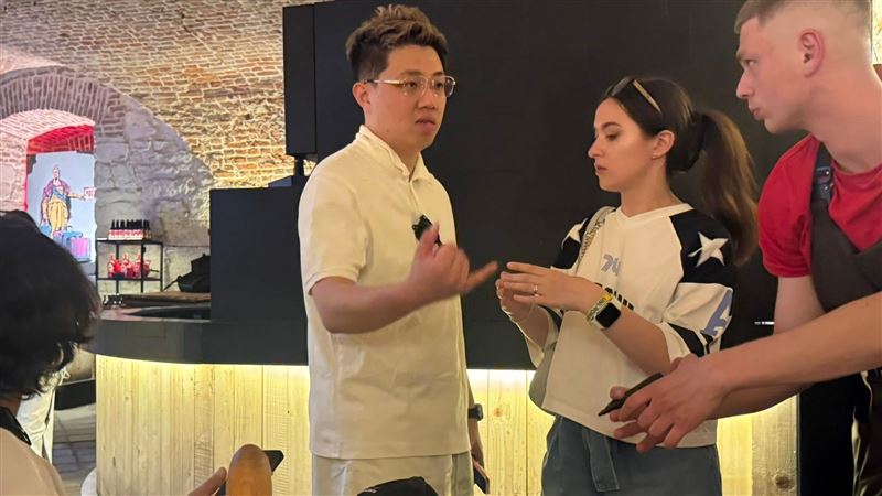 從台灣的某大學電機系畢業後,奔赴戰火基輔,許丞巽在無人機設計專業中實戰求學。經歷宿舍遭轟炸的生死瞬間,他看見烏克蘭社會在恐懼與通膨中展現的韌性。這段用兩年青春換來的戰地觀察,不僅是無人機技術的震撼進化,更是一份留給台灣關於和平價值的深刻告白。圖中白衣男即為許丞巽,他正與貿協駐基輔辦事處員工討論工作事宜。(圖/記者師瑞德攝影)
