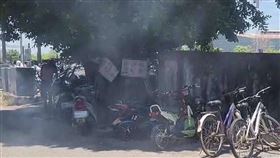 一名男子撿拾枯枝落葉生火烤魚，現場濃煙密布。（民眾提供）