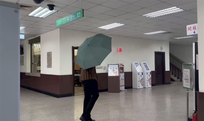 斑霸進入高等法院時,突兀地撐起雨傘想阻擋媒體拍攝。(圖/翻攝畫面)