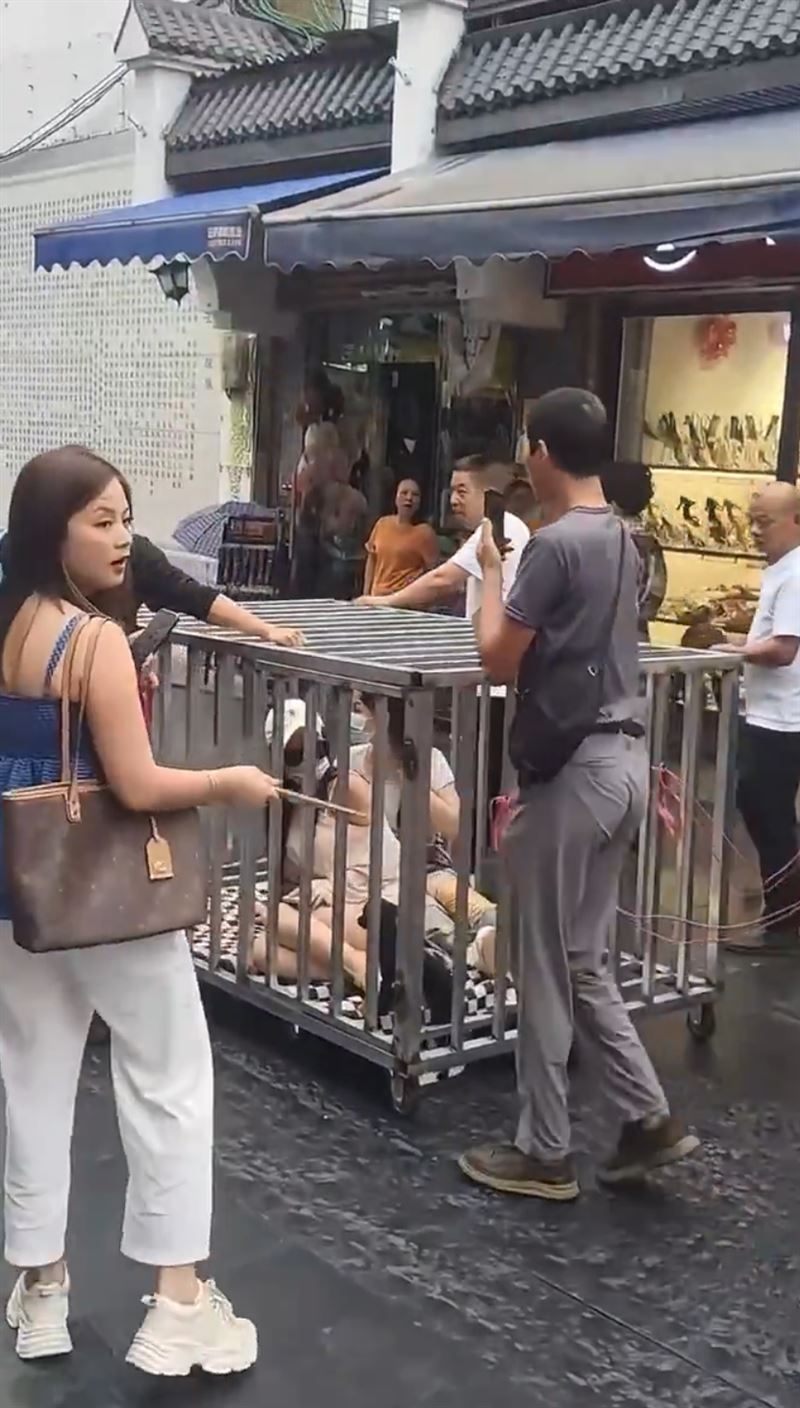 中國「2女1狗」遭關籠遊街，籠外還懸掛「偷人的」紙板，引發熱議。（圖／翻攝自X）