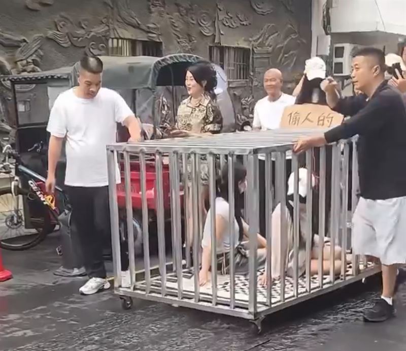 中國「2女1狗」遭關籠遊街，籠外還懸掛「偷人的」紙板，引發熱議。（圖／翻攝自X）
