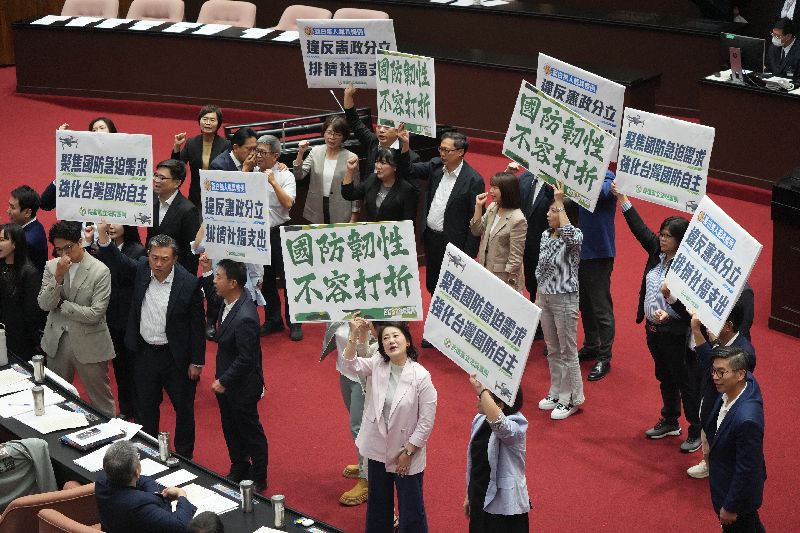 民進黨立委籲國防韌性不容打折立法院3日上午召開院會，在處理報告事項時，朝野黨團無異議，將國民黨團所提「國防自主無人載具科技發展及採購條例草案」、民眾黨團所提「強化國防自主暨無人機產業發展條例草案」，交付立法院經濟、外交及國防、財政3委員會審查。圖為民進黨立委在議場中舉牌喊口號表達立場。(圖／中央社）