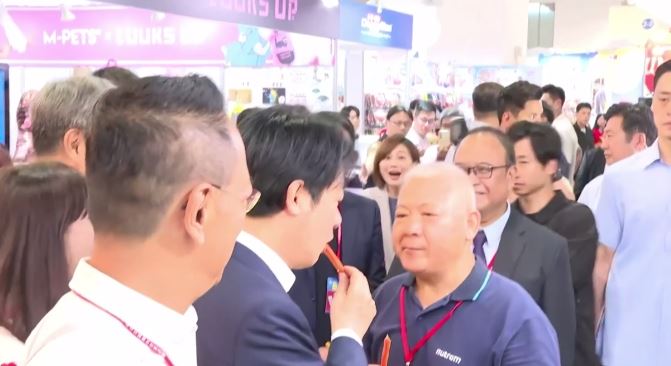 總統賴清德逛寵物展試吃天然寵物雞肉條肉乾，隨行的總統府發言人郭雅慧驚訝地瞪大眼（圖／翻攝畫面）