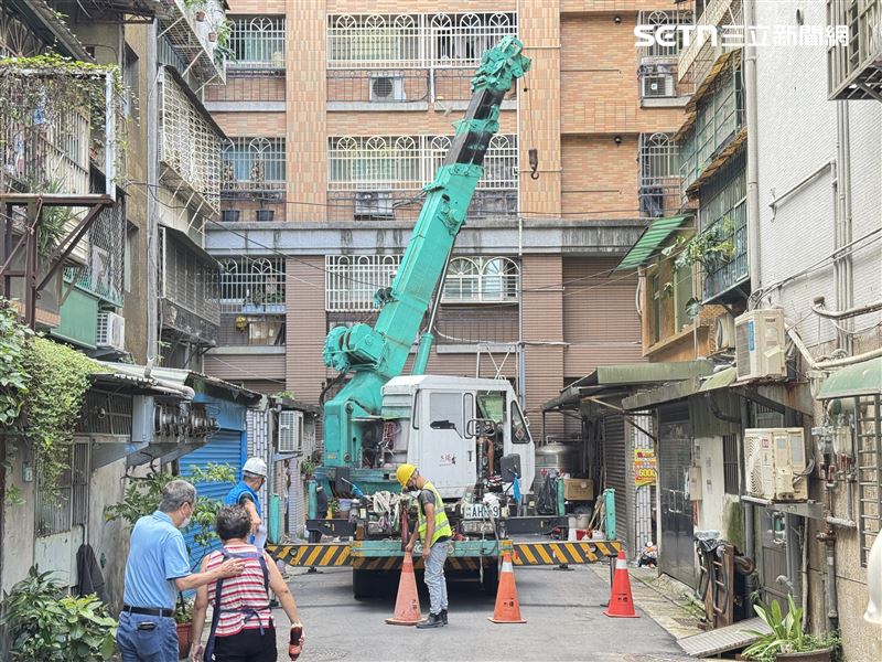 吊車將堆放多年的大型家具、廢棄家電及鐵皮等物品逐一吊離頂樓。(圖/記者鍾釗榛攝影)