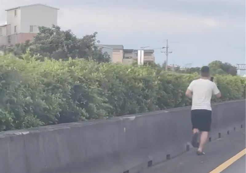 「路跑男」闖入國道,拿著手機在內側路肩處路跑。(圖/翻攝自Threads @wangyunchen31)
