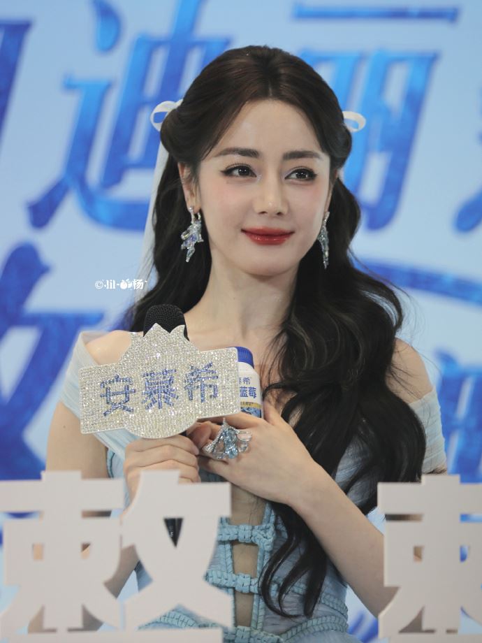 因禮服深V設計又缺乏支撐,迪麗熱巴全程不斷拿代言商品或麥克風遮擋胸口,避免走光。(圖/翻攝自微博)