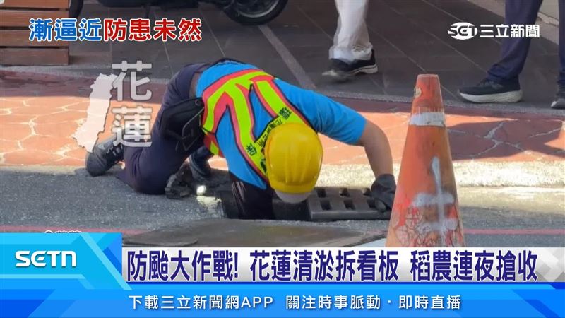 工作人員趴在地面清理水溝髒污