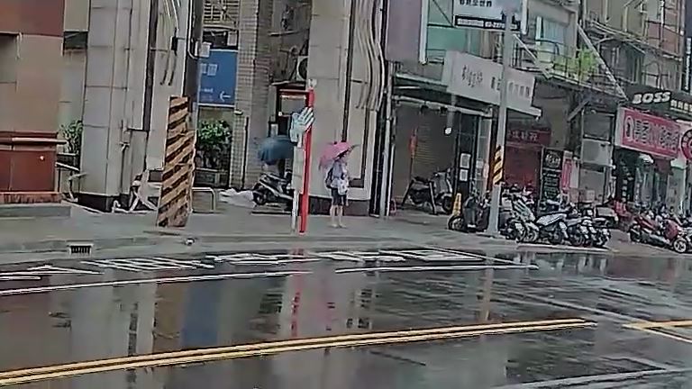 婦人撐著雨傘站在路口。(圖/翻攝畫面)
