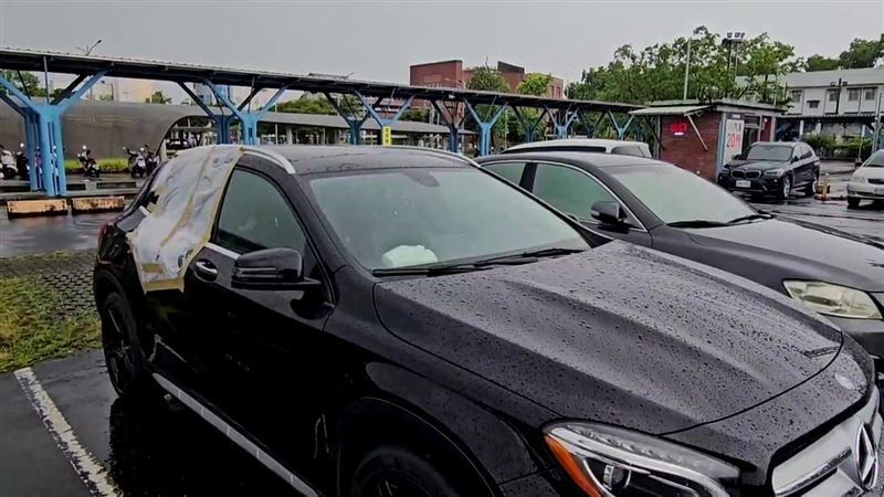 宜蘭轉運站停車場內一輛黑色賓士車的後車窗沒關,附近居民以塑膠袋和膠帶協助「封窗」。(圖/翻攝畫面)