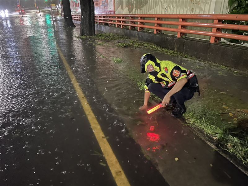 2名員警頂著暴雨蹲在路邊徒手清理排水溝。（圖／翻攝畫面）