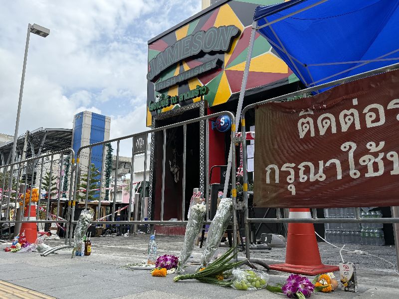 泰國曼谷啤酒餐廳發生重大火災後,門外圍起封鎖線,有民眾在地上擺放鮮花悼念罹難者。警方持續調查起火原因,並釐清場所登記類別是否與實際經營型態相符