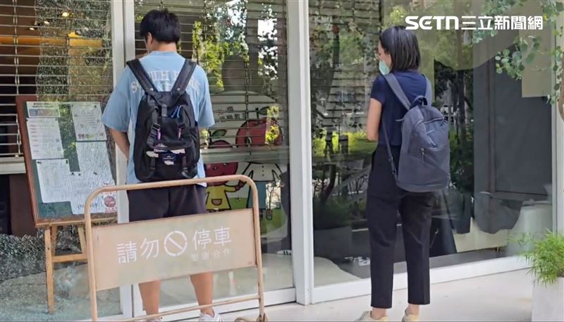 小妹(黑衣者)在親友陪同下,首度神情哀戚地重回到事發現場。現場不僅一片狼藉,音樂教室大門的厚實玻璃更是因昨日的激烈衝突與隨後的警匪槍戰而「碎裂成蜘蛛網狀」。(圖/翻攝畫面)