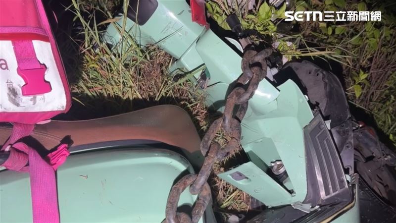 外送員猛烈撞上岸際鐵鍊,機車卡在原地,人被拋飛至前方草叢堆。(圖/翻攝畫面)