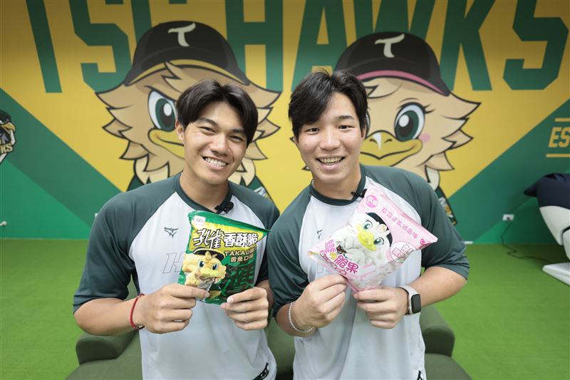 台鋼球員林家鋐(左)、紀慶然搶先開吃台鋼雄鷹聯名乖乖,鹹香「TAKAO最愛香魚口味」孔雀香酥脆和夢幻粉紅「TAKAMEI草莓雞蛋糕彎的脆果」雙口味限量登場。(圖/乖乖提供)