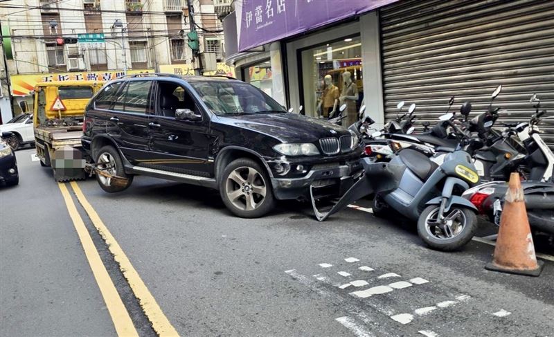 拖吊車轉彎時操作不慎,導致拖掛在後方的報廢車撞倒數輛機車。(圖/翻攝畫面)