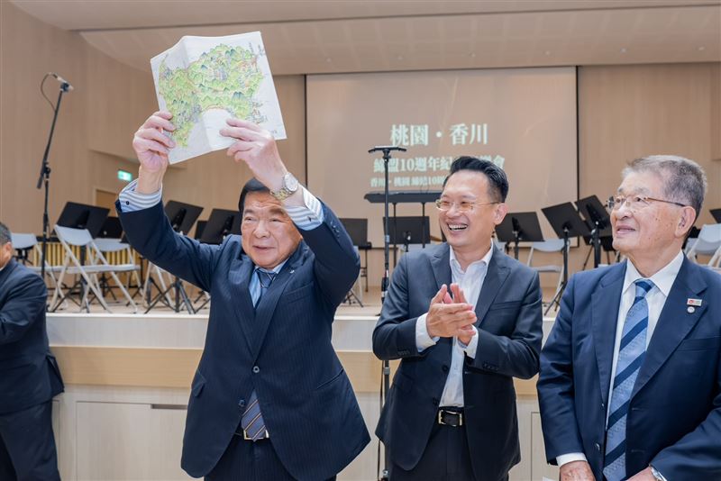 桃園市副市長蘇俊賓(中)贈送自製的由高松市出發的「四國旅行地圖手札」給鎌田守恭議員(左)。(圖/桃園市政府提供)