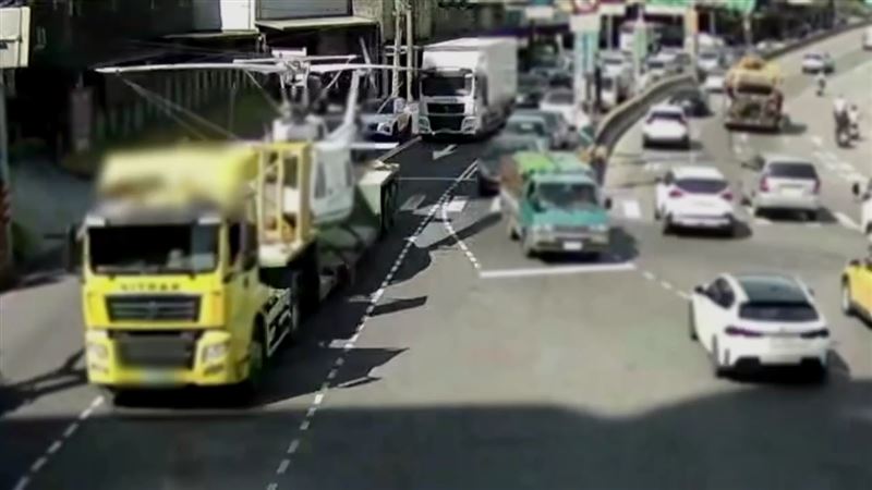 一輛曳引車載運直升機行經汐止大同路時,直升機螺旋槳撞上監視器機箱、勾落電纜線,導致號誌故障,交通大亂。(圖/翻攝畫面)