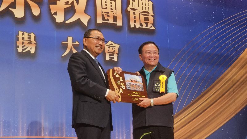 新北市政府4日舉辦績優宗教團體表揚大會,市長侯友宜(左)出席頒獎並感謝各宗教團體的公益捐助及社會教化貢獻,板橋埔墘福德宮主委廖榮清(右)上台領獎