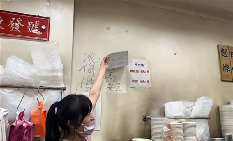 百年老字號「東發號麵線」的老闆娘熱情邀請沈伯洋在店裡牆上簽名,沒想到老闆娘將台北市長蔣萬安的簽名蓋掉。(圖/翻攝自周軒臉書)