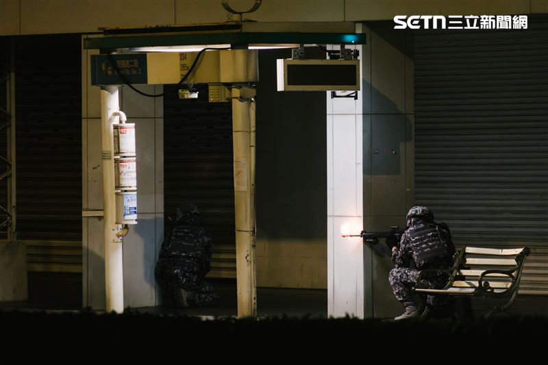 以騎樓、公車站為掩護的我軍士兵向進犯敵軍開火。（圖／記者楊士誼攝影）