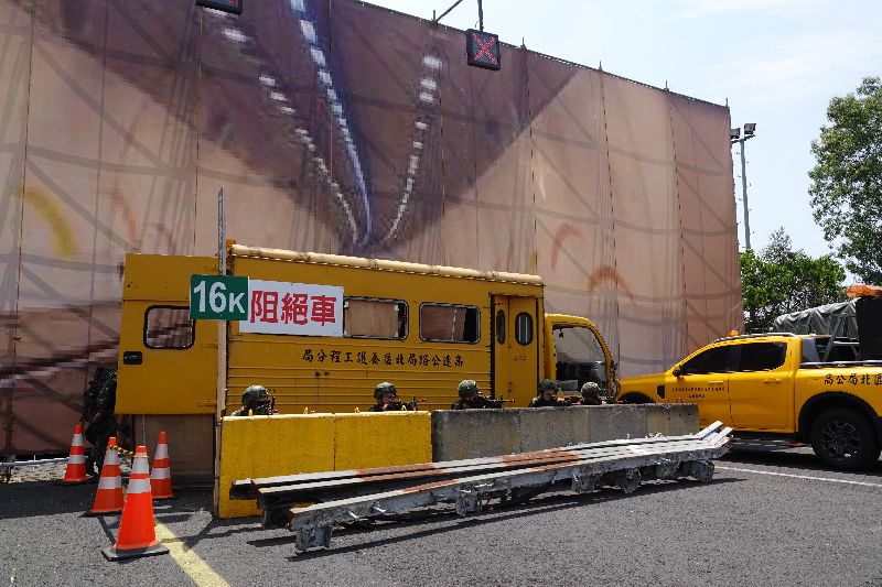國軍與高工局13日在高公局頭城工務段舉行「雪山隧道封阻縮短距離實兵演練」,陸軍官兵以紐澤西護欄與報廢車輛所組成的道路阻絕,作為掩護進行防守。(圖/中央社)