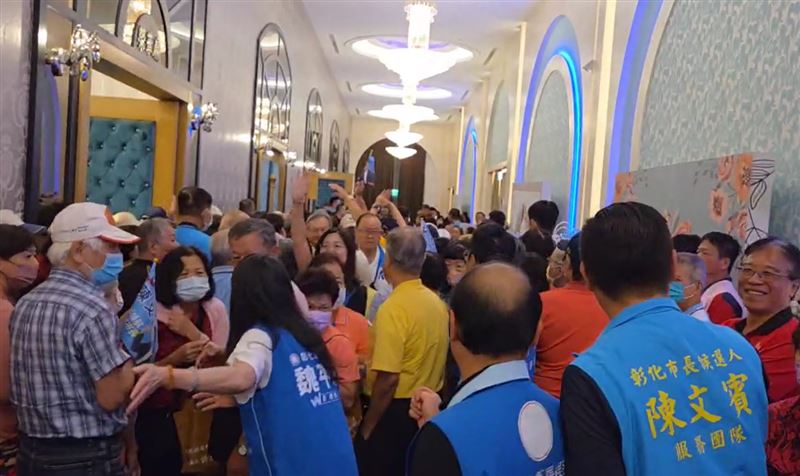 後方民眾誤以為活動已結束,急著往大門走領餐盒,被志工勸回座位,現場鬧哄哄。(圖/翻攝畫面)
