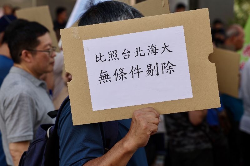 內政部17日召開社子島土地徵收審議小組專案會議,社子島自救會等團體到場表達訴求,民眾手持「比照台北海大 無條件剔除」標語,要求將既有聚落剔除區段徵收範圍