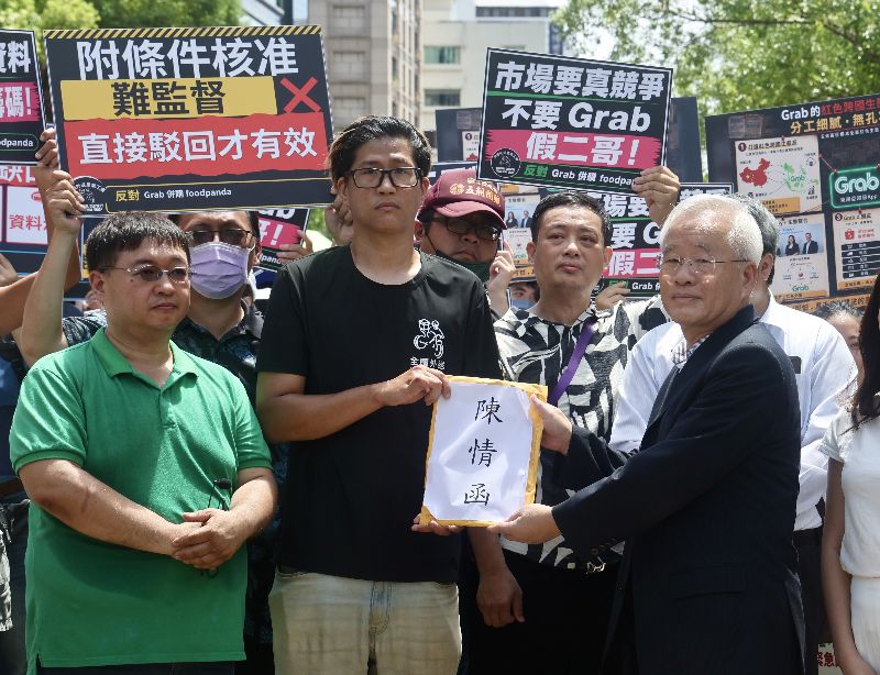全國外送產業工會等團體18日在公平交易委員會前舉行記者會，針對Grab併購foodpanda表達強烈反對，全國外送產業工會理事長陳昱安（前中）遞交陳情書給公平會代表
