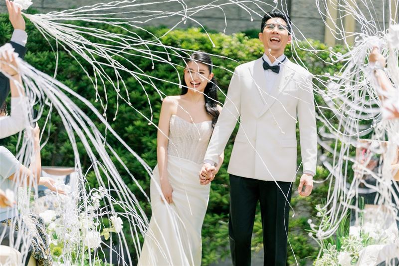 白色拉炮如繁花灑落,新人在歡笑與掌聲中牽手步向新人生,將戶外證婚派對的氣氛推向最高潮。(圖/飯店旅宿業者提供)