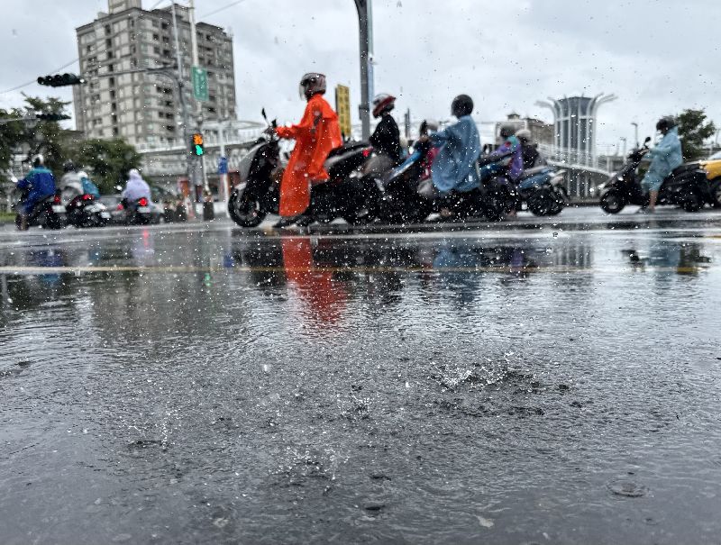 氣象署多日針對南高屏與花蓮發布大雨特報,高雄市前鎮區下起雨,穿雨衣的機車騎士在雨中停等紅燈