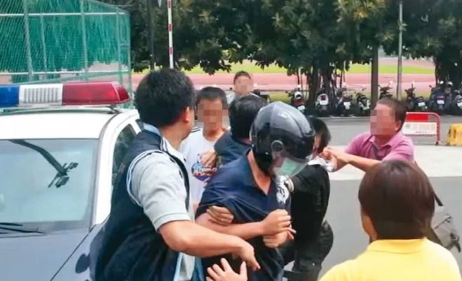 縱火的情侶檔被帶回警局時,黃家親友氣憤追打呂男。(翻攝蘋果新聞網)