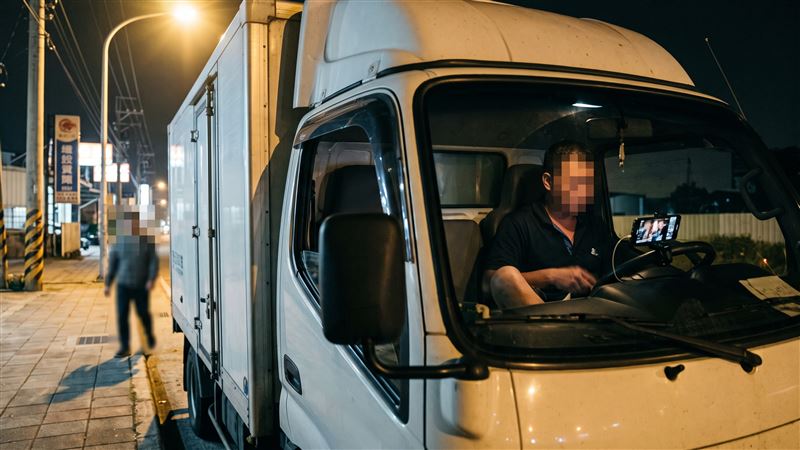 貨車司機晚上坐在駕駛座,停靠在路燈明亮處,把車窗搖下,手機放在方向盤前方播放成人影片,手部做出不雅動作,被路人直擊。(示意圖/AI製圖)