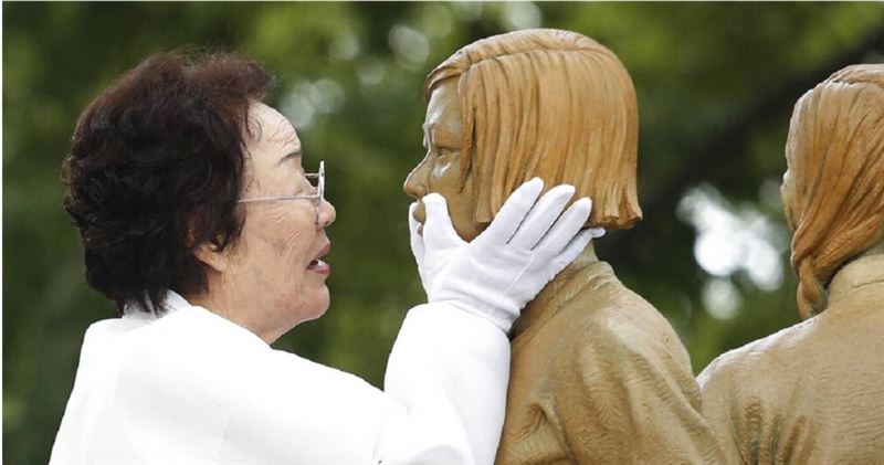 2019年8月14日,韓國慰安婦倖存者李容洙在象徵二戰時期慰安婦問題的女孩雕像揭幕儀式上,觸摸雕像的臉龐。(圖/達志/美聯社)