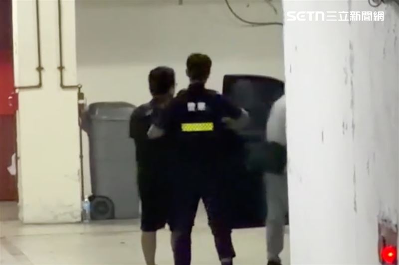 吳男抵達地檢署下警車時,樣貌身形首度在鎂光燈前曝光。他身穿深色上衣與長褲,雙手被警方冰冷的手銬緊緊銬住。(圖/翻攝畫面)