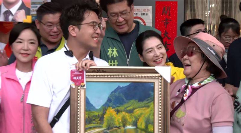 民進黨台北市長參選人沈伯洋今(20)日赴北投市場外攤掃街,一名鄉親帶了得獎畫作給沈簽名。(圖/翻攝畫面)