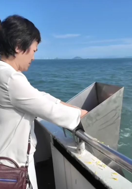 陳觀泰相差30歲的遺孀湯利萍親自捧著丈夫骨灰,撒入大海。(圖/翻攝自微博)