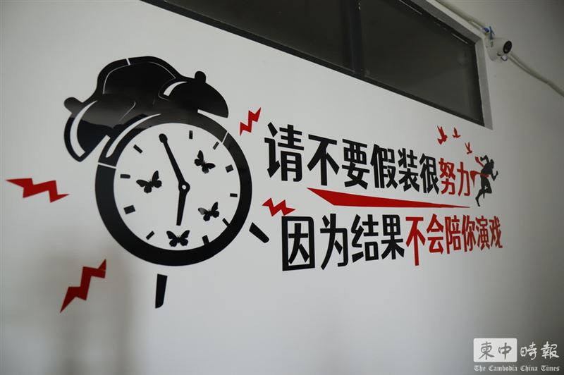 辦公室牆上貼著如「請不要假裝很努力,因為結果不會陪你演戲」簡體字。(圖/翻攝自柬中時報)