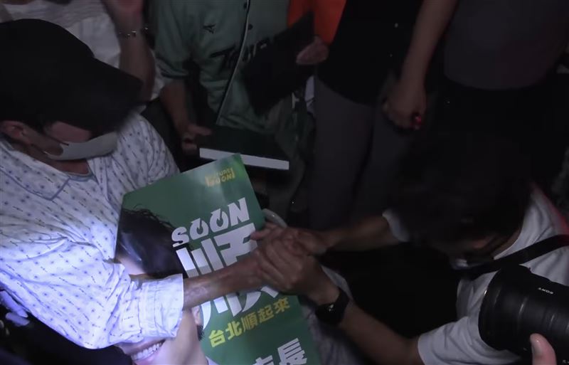 沈伯洋掃街時遇到坐輪椅的長輩,他隨即蹲下握住對方雙手,喊道「足歹勢,今天掃得比較慢」。(圖/翻攝畫面)