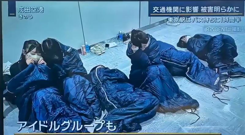杜鵑颱風侵襲日本關東,近4千人受困成田機場,新聞畫面掃到女團成員集體「睡機場」。(圖/翻攝自X@雪乃椛鈴)