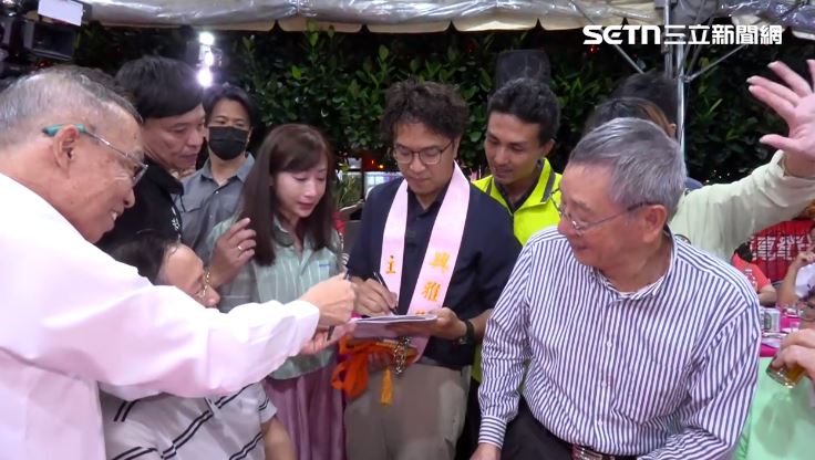沈伯洋出席興雅福德宮中秋聯歡餐會,替現場民眾簽名。(圖/翻攝畫面)