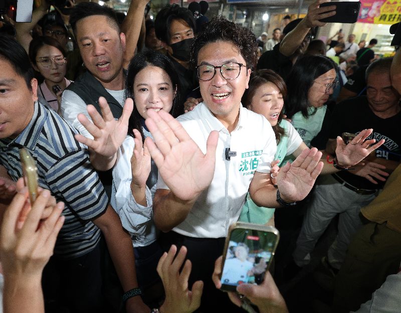 民進黨台北市長參選人沈伯洋(前中)26日晚間出席「台北市中庄仔福德宮福德正神聖誕千秋晚宴」,進場時和民眾擊掌致意,互動熱絡。(圖/中央社)