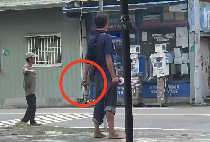 男子手持孔明扇與菜刀當街咆哮。(圖/翻攝自爆料公社)