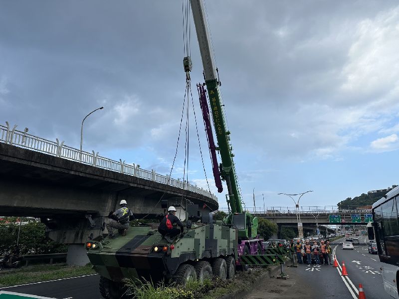 一輛國軍雲豹甲車2日清晨行經新北淡水關渡大橋匝道時自撞分隔島,造成燈桿斷裂,一度影響交通,軍方委託吊車將雲豹甲車拖離事故現場。(翻攝照片)