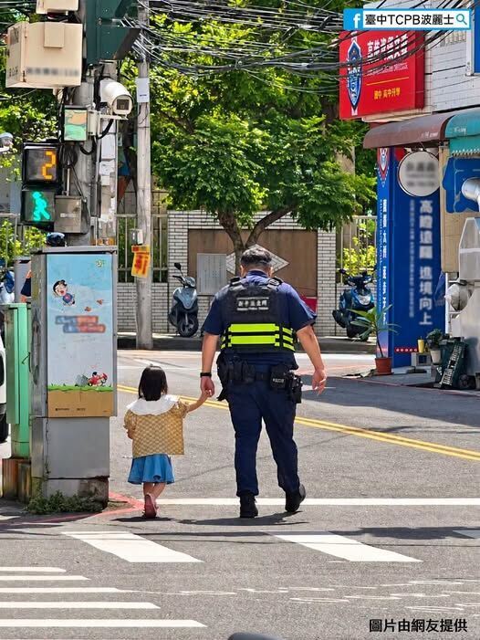 員警與小女孩一高一矮的畫面,猶如「毛怪」護送「阿布」的經典橋段。(圖/翻攝畫面)