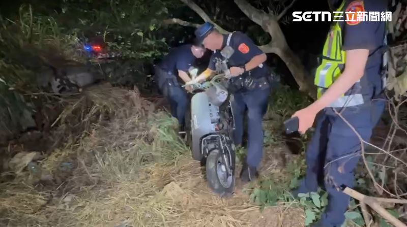 處理事故的員警，把肇事撞毀的機車從邊坡拖出。（圖／翻攝畫面）