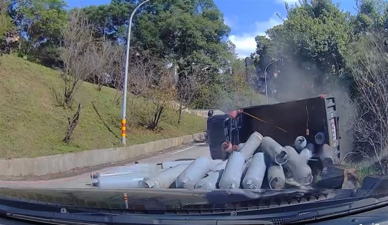 貨車向後倒退後，右後輪撞上路邊緣石導致整輛車翻覆，車上的瓦斯鋼瓶也散落一地。（圖／Threads @truly_man_ivan授權提供）