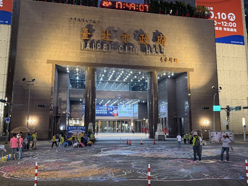 台北市政府10日國慶當天將在市府前廣場舉辦115年國慶升旗暨慶祝活動,除升旗外,活動亮點還包括把市府路變成大型畫布。9日傍晚場布時,已有民眾開始彩繪